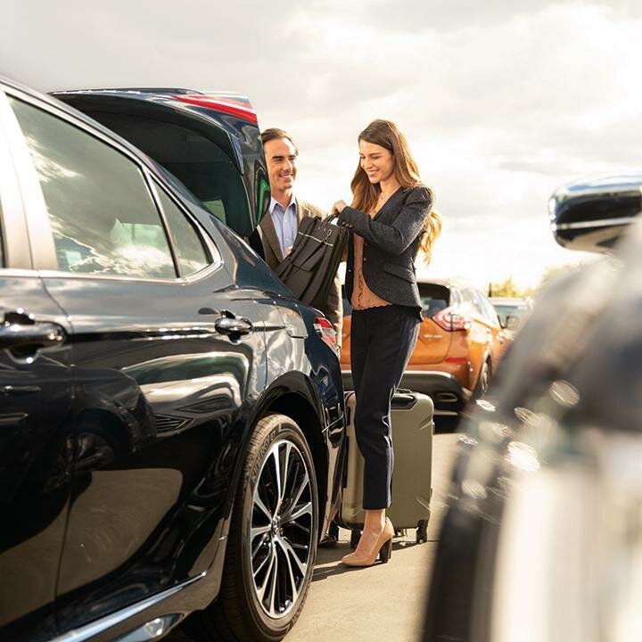 Travelers loading luggage into a rental vehicle
